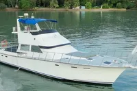 Custom 1984 project boat with blue canopy, anchored in serene waters near lush shoreline.