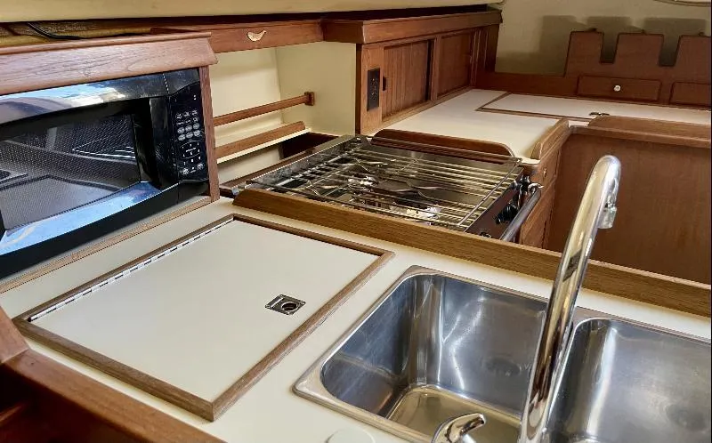  Yacht Photos Pics Interior view of 1999 Island Packet 380 yacht kitchen with sink, stove, and microwave.