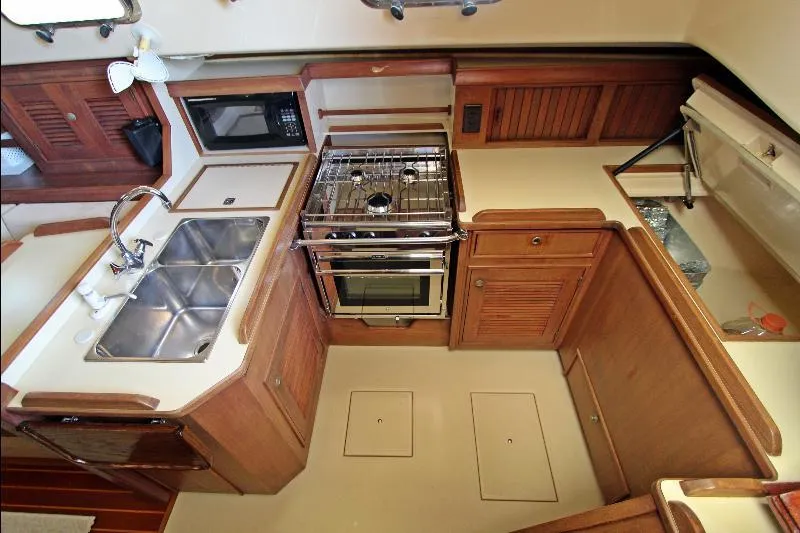  Yacht Photos Pics 1999 Island Packet 380 yacht kitchen with stove, sink, and wooden cabinetry.