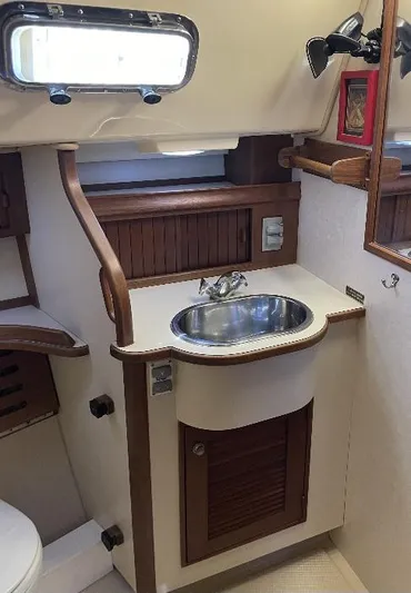  Yacht Photos Pics 1999 Island Packet 380 yacht bathroom with sink, mirror, and wooden cabinetry.