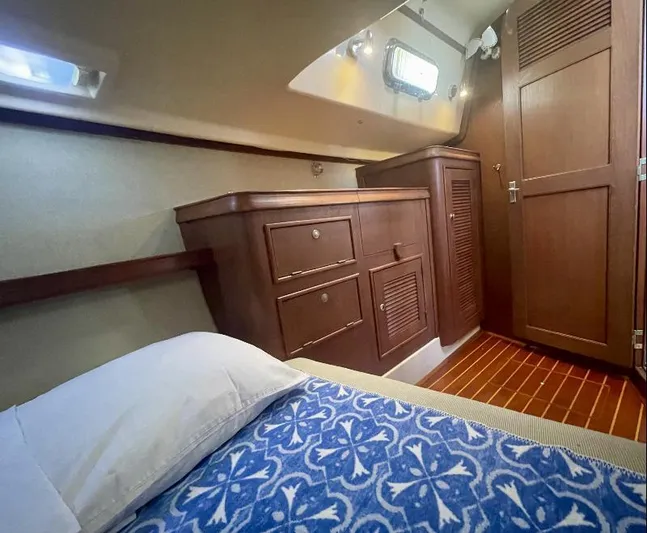  Yacht Photos Pics Cozy cabin interior of 1999 Island Packet 380 sailboat with wooden cabinetry and blue patterned bedding.