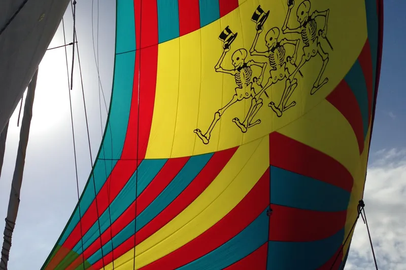  Yacht Photos Pics Colorful sail with skeleton design on Island Packet 380, 1999 model, against a bright sky.