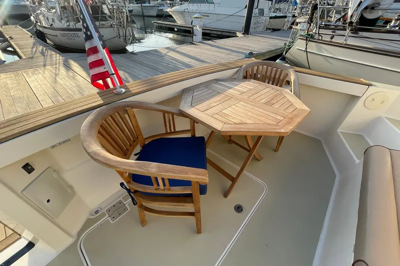 Ocean Breeze Yacht Photos Pics 2008 Sabre 38 Salon Express yacht deck with wooden chairs and table, docked at marina.