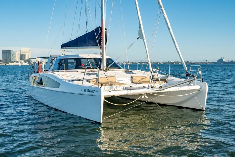 Sugarloaf Yacht Photos Pics 2023 Seawind 1160 Lite catamaran sailing on calm waters near a city skyline.