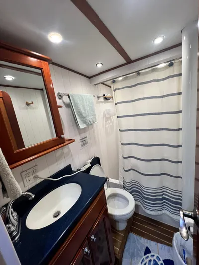 No Good Deed Yacht Photos Pics Bathroom interior of 2007 Great Harbour N47 yacht with sink, toilet, and striped shower curtain.