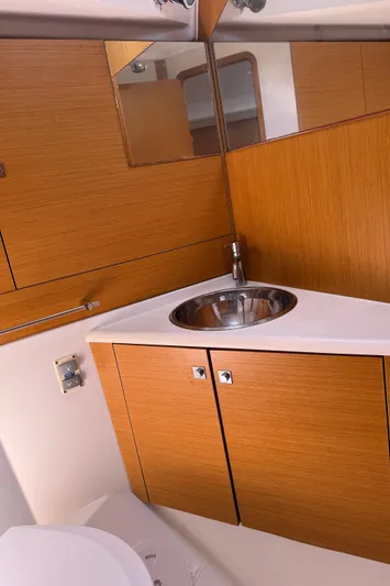  Yacht Photos Pics Bathroom interior of 2011 Jeanneau Sun Odyssey 45 DS yacht, featuring wooden cabinetry and stainless steel sink.