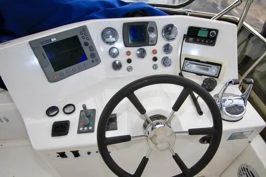 Smitten Yacht Photos Pics Control panel of a 2006 Harbor Master Coastal 400 boat with steering wheel and navigation instruments.