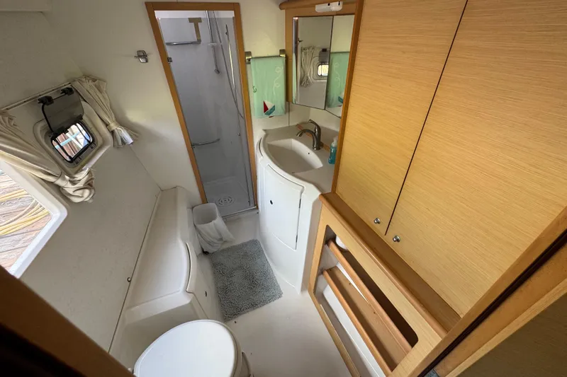 Willow Yacht Photos Pics Interior of 2008 Lagoon 420 yacht bathroom with shower, sink, and wooden cabinetry.