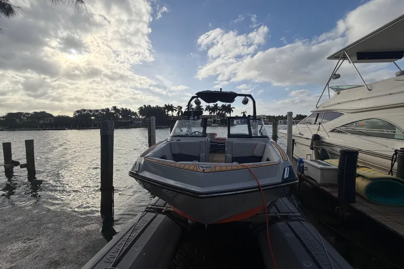 Coastal Edition Yacht Photos Pics 2022 Nautique Super Air Nautique G25 docked at marina under cloudy sky.