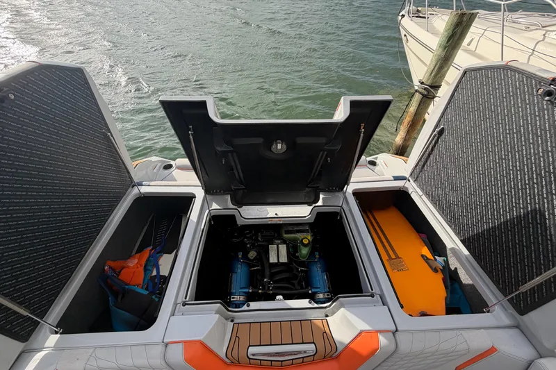 Coastal Edition Yacht Photos Pics 2022 Nautique Super Air Nautique G25 engine compartment with storage, docked by water.