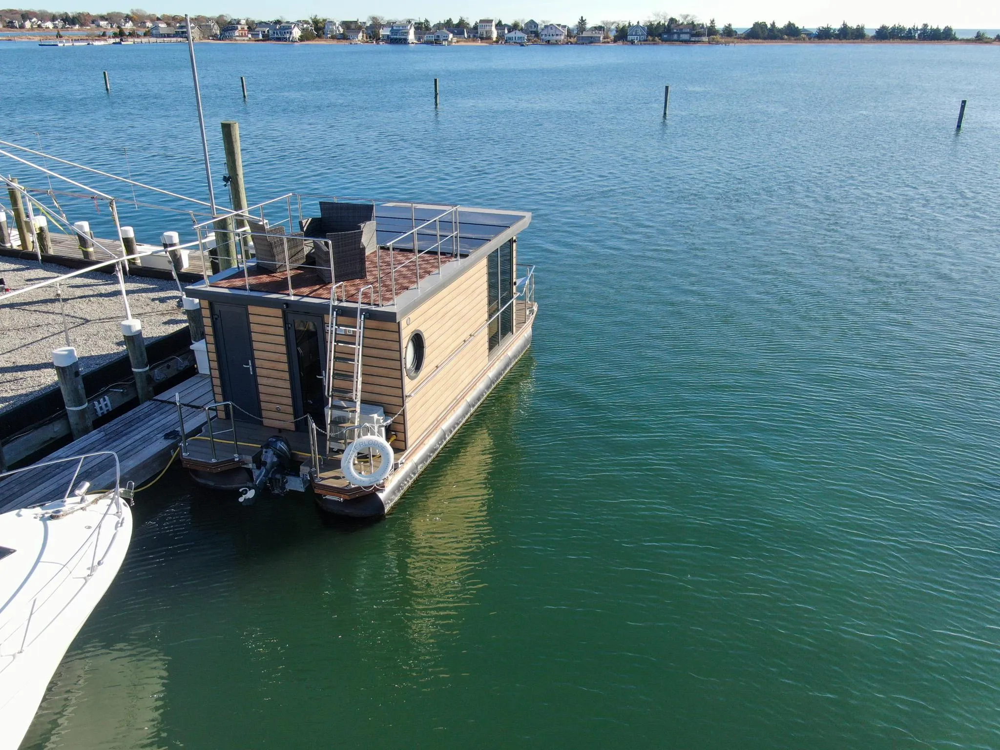 Houseboat Waterlodge Apart M 2024 docked on calm water, with scenic shoreline view.