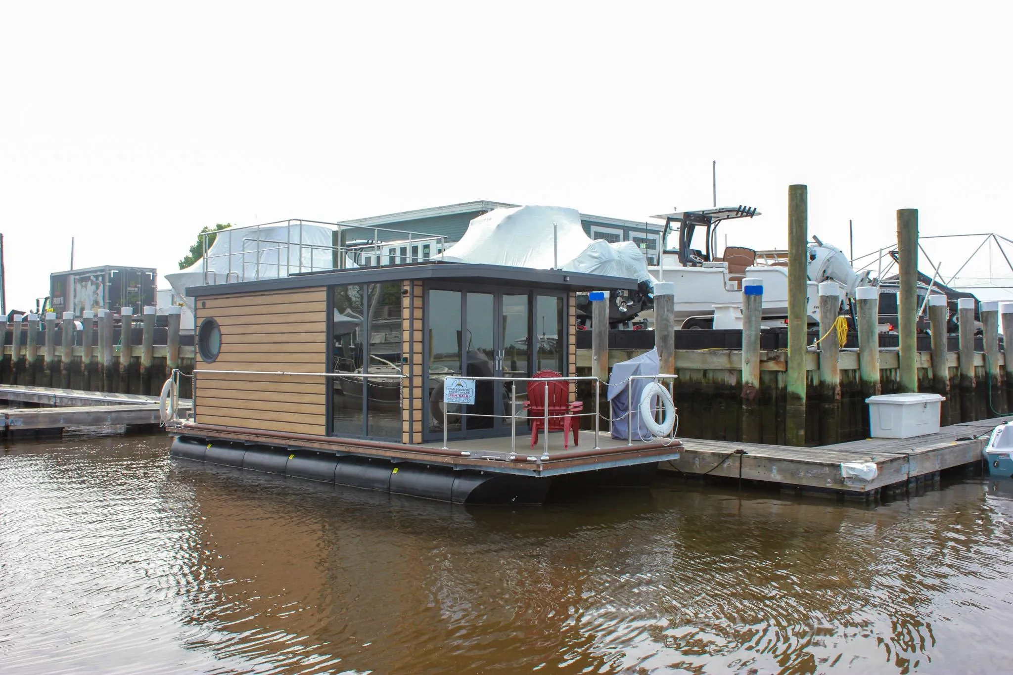 2024 Waterlodge Apart M houseboat docked at marina, featuring modern design and glass windows.