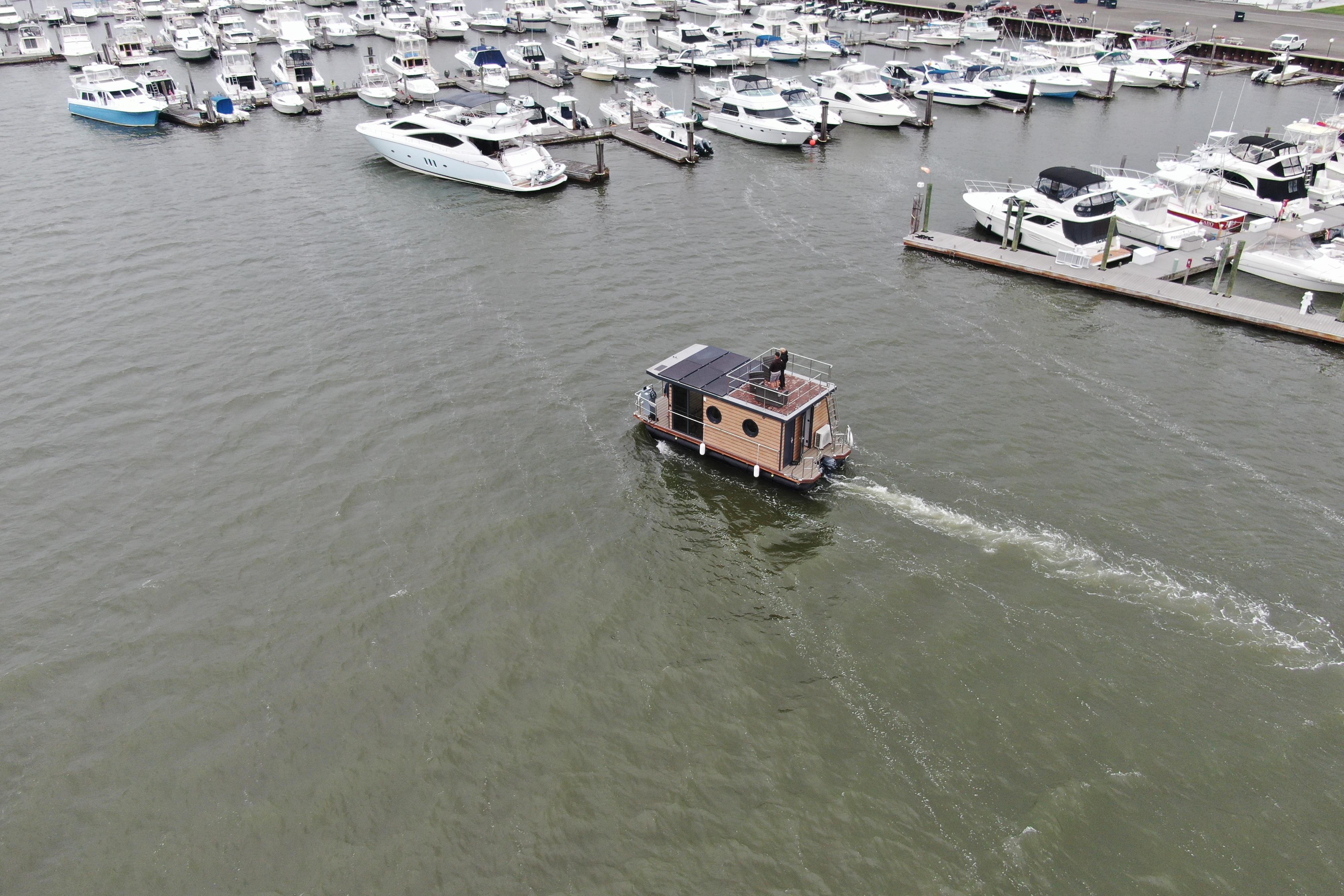 Aerial view of 2024 Waterlodge Apart M houseboat navigating a marina with docked boats.