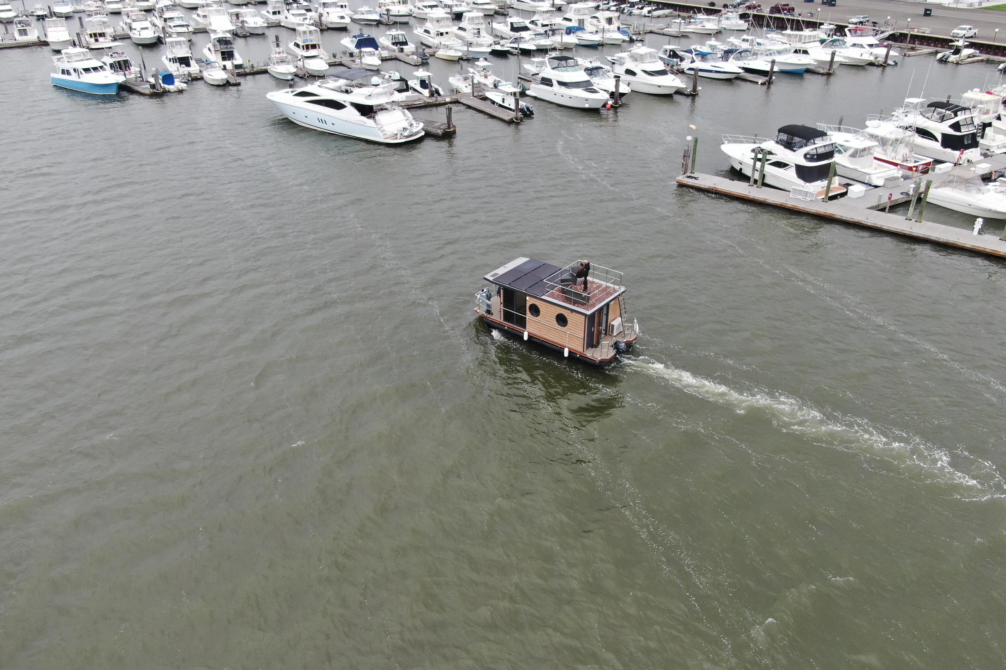 Aerial view of 2024 Waterlodge Apart M houseboat navigating a marina with docked boats.