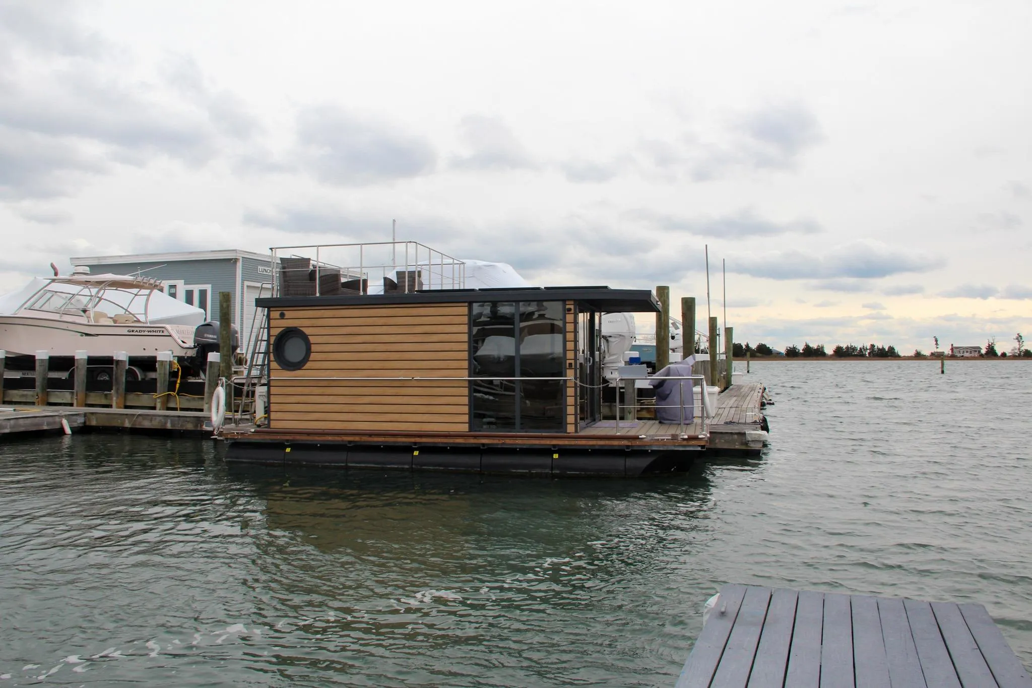 Modern 2024 Waterlodge Apart M houseboat docked on a serene waterfront.