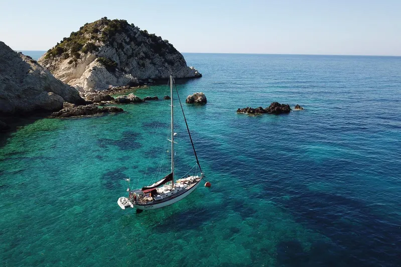 Talaria Yacht Photos Pics Sailboat Tayana Vancouver 42, 1988, anchored in clear turquoise waters near rocky island.