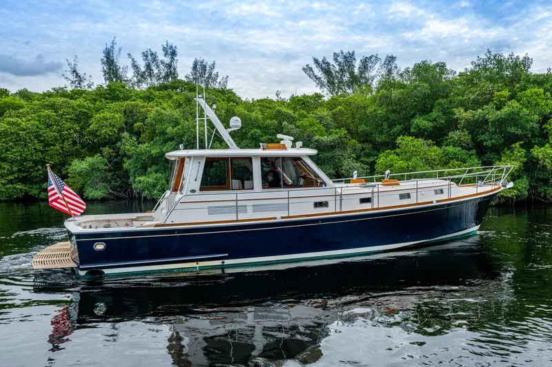 Bright Star Yacht Photos Pics 2003 Grand Banks 49 Eastbay HX yacht cruising near lush green shoreline.
