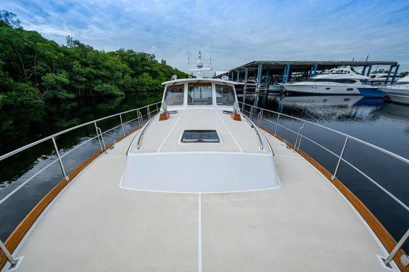 Bright Star Yacht Photos Pics 2003 Grand Banks 49 Eastbay HX yacht docked near lush greenery and marina.