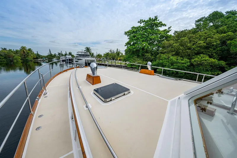 Bright Star Yacht Photos Pics 2003 Grand Banks 49 Eastbay HX yacht deck with railing, docked near lush greenery.