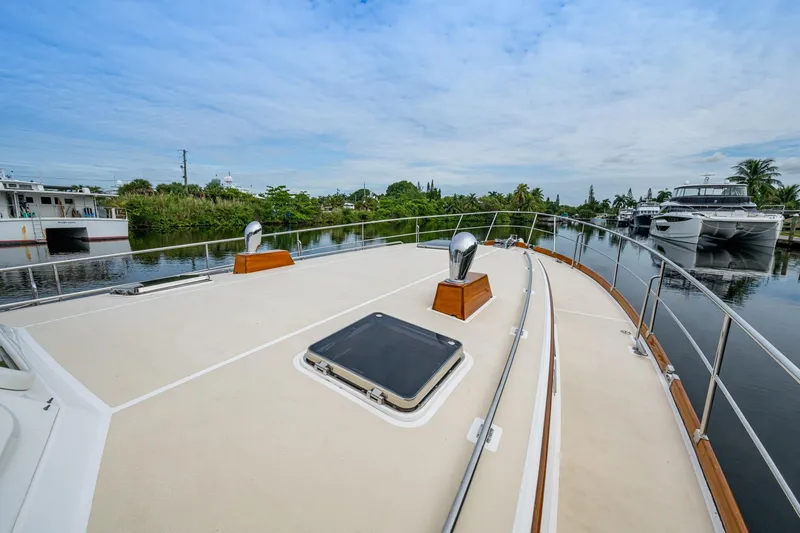 Bright Star Yacht Photos Pics 2003 Grand Banks 49 Eastbay HX yacht deck with railing, docked near lush greenery.