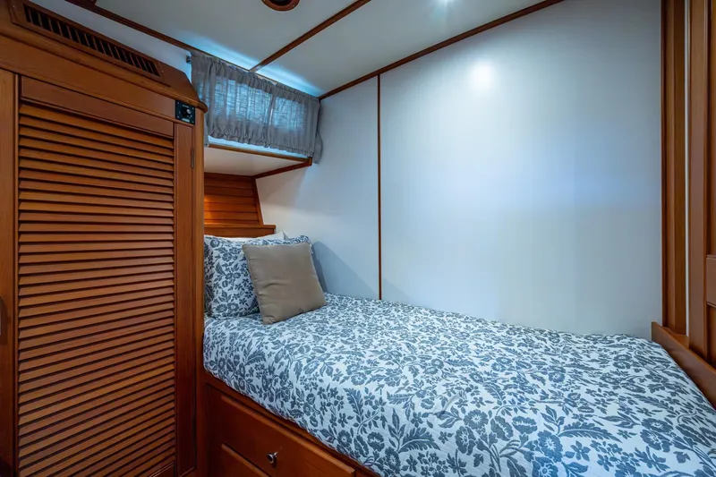 Bright Star Yacht Photos Pics Cozy cabin interior of 2003 Grand Banks 49 Eastbay HX with floral bedding and wooden accents.