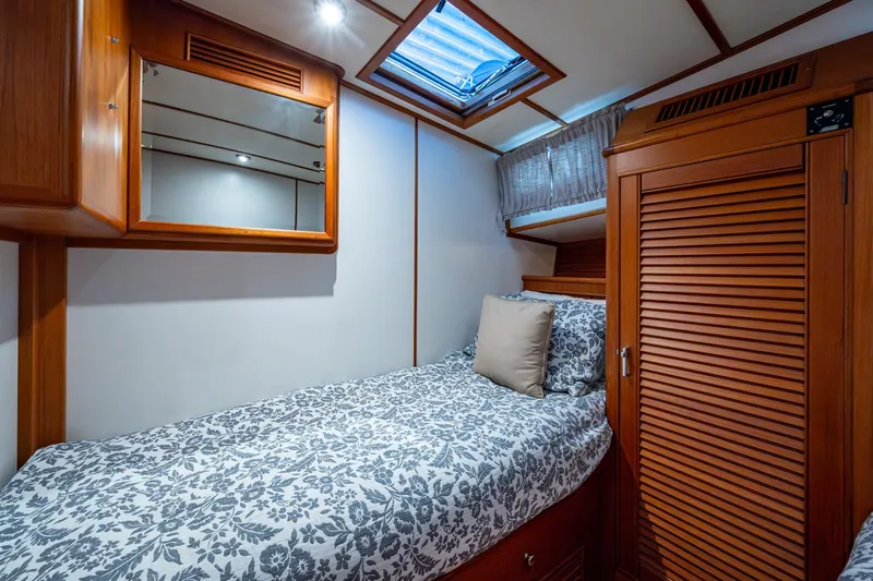 Bright Star Yacht Photos Pics Cozy cabin interior of 2003 Grand Banks 49 Eastbay HX with floral bedding and wooden accents.