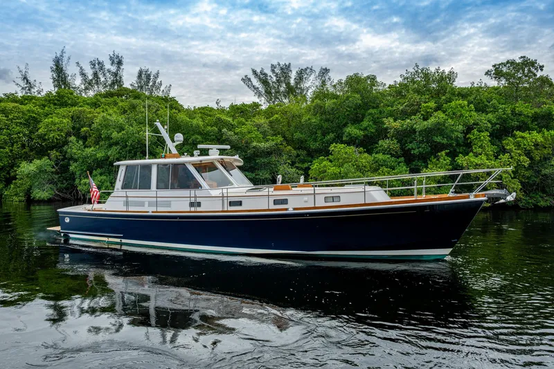 Bright Star Yacht Photos Pics 2003 Grand Banks 49 Eastbay HX yacht cruising on calm waters, surrounded by lush greenery.