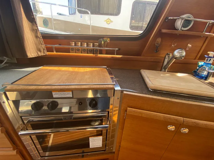 Sal-taire Yacht Photos Pics 2016 Ranger Tugs R-29S kitchen with stove, sink, and wooden cabinetry.