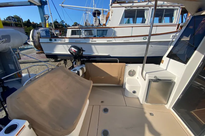 Sal-taire Yacht Photos Pics 2016 Ranger Tugs R-29S boat deck with seating and motor, docked near another vessel.