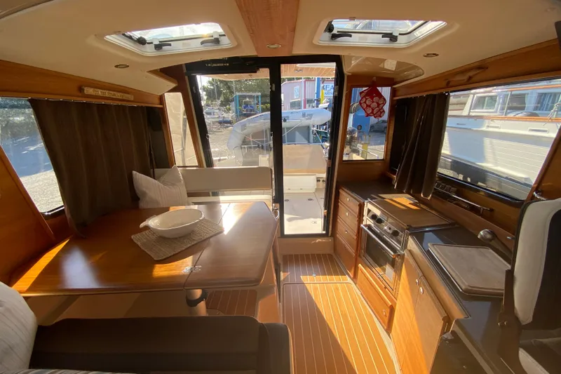 Sal-taire Yacht Photos Pics Interior of 2016 Ranger Tugs R-29S, featuring dining area and kitchen with wood accents.