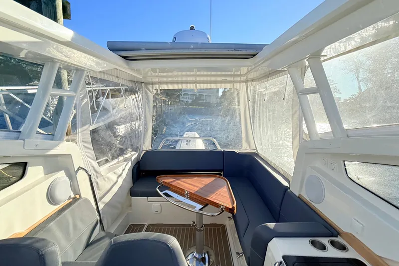 Yucca Flats Yacht Photos Pics 2023 Nimbus Weekender 9 interior with seating, wooden table, and clear windows on a sunny day.