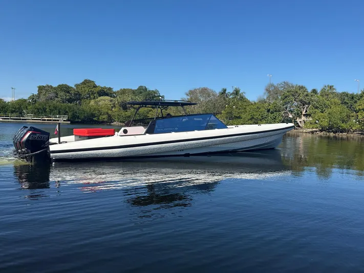  Yacht Photos Pics 2024 Goldfish 46 Open boat on calm water, surrounded by lush greenery.