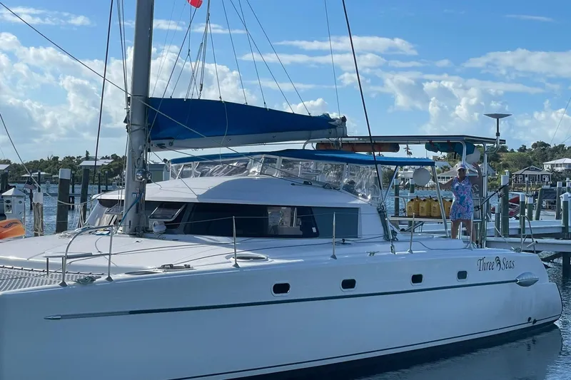 Three Seas Yacht Photos Pics 2002 Fountaine Pajot Belize 43 catamaran docked, named "Three Seas," with a person onboard.