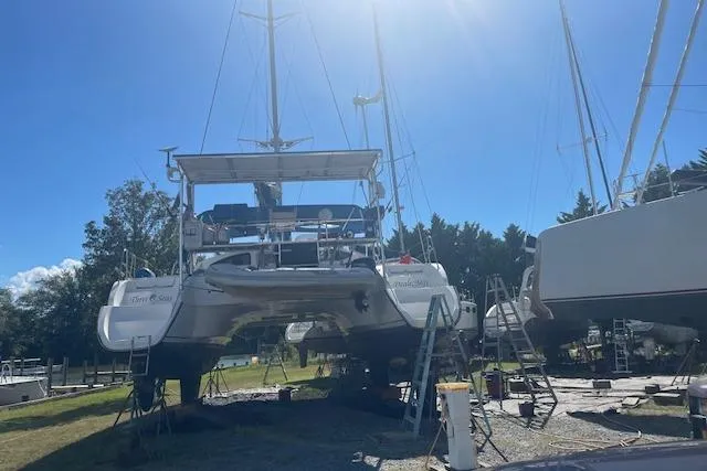 Three Seas Yacht Photos Pics 2002 Fountaine Pajot Belize 43 catamaran on land, surrounded by trees and clear sky.