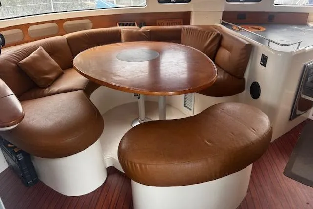 Three Seas Yacht Photos Pics Interior of 2002 Fountaine Pajot Belize 43 with brown leather seating and wooden table.
