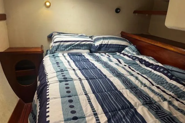 Three Seas Yacht Photos Pics Cozy cabin bedroom in 2002 Fountaine Pajot Belize 43 with striped bedding and wooden accents.