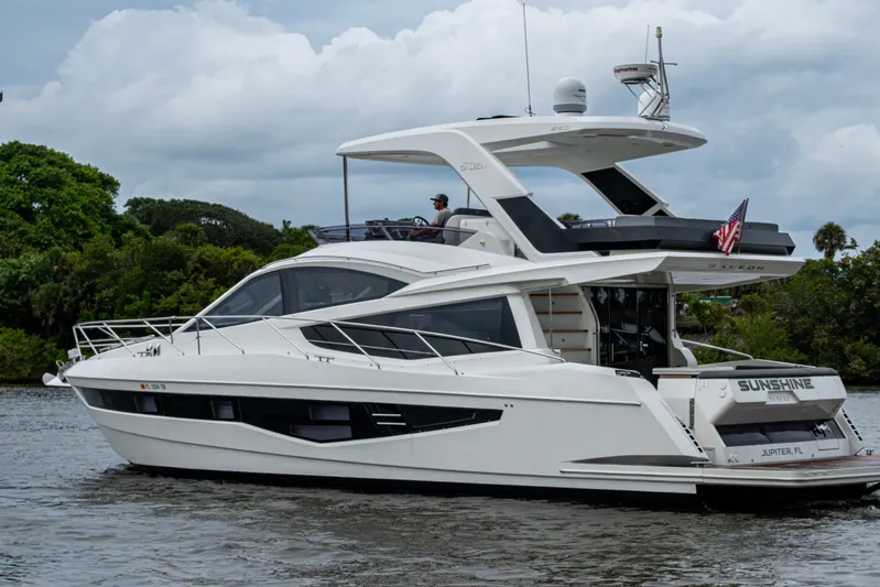 Sunshine Yacht Photos Pics 2020 Galeon 550 Fly yacht cruising on a river with lush greenery in the background.