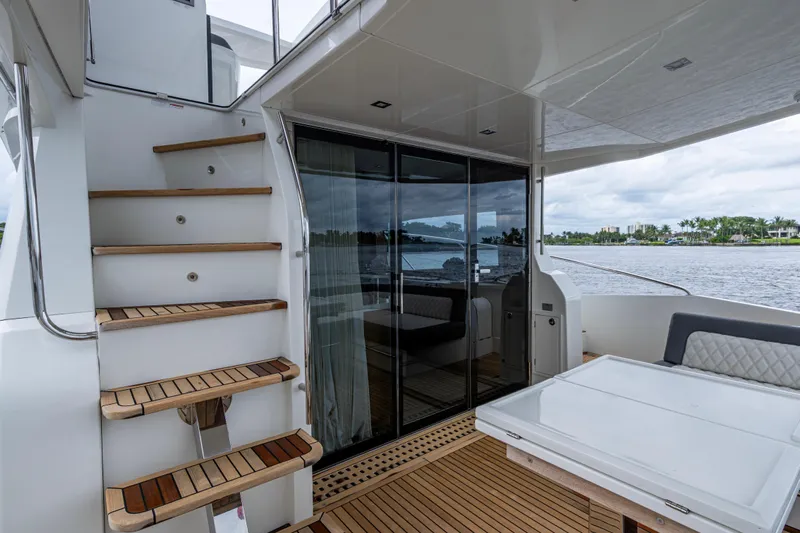 Sunshine Yacht Photos Pics 2020 Galeon 550 Fly yacht interior with wooden stairs and glass doors, overlooking water.