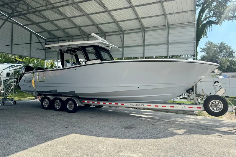 No Joke Yacht Photos Pics 2022 Robalo R360 Center Console boat on trailer under metal canopy.