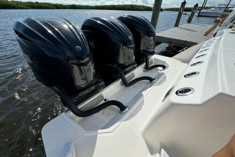 No Joke Yacht Photos Pics Triple outboard engines on a 2022 Robalo R360 Center Console boat docked by the water.