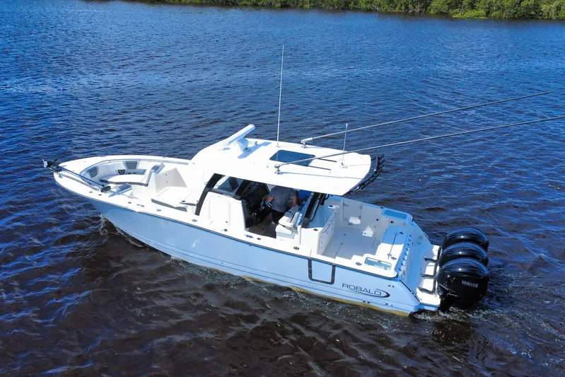 No Joke Yacht Photos Pics 2022 Robalo R360 Center Console boat cruising on a calm blue lake.