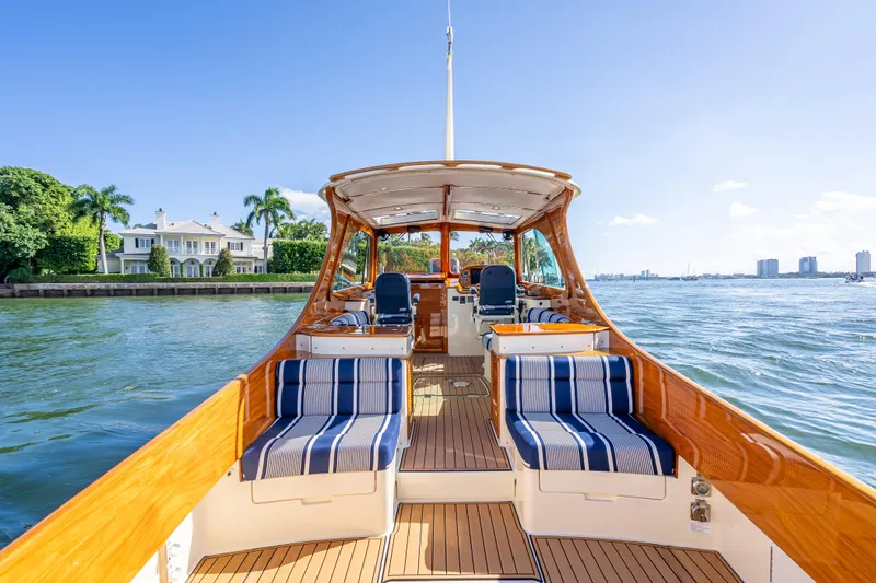 Gracious Yacht Photos Pics 2018 Hinckley Picnic Boat 37 MKIII cruising near waterfront estate, clear blue sky.
