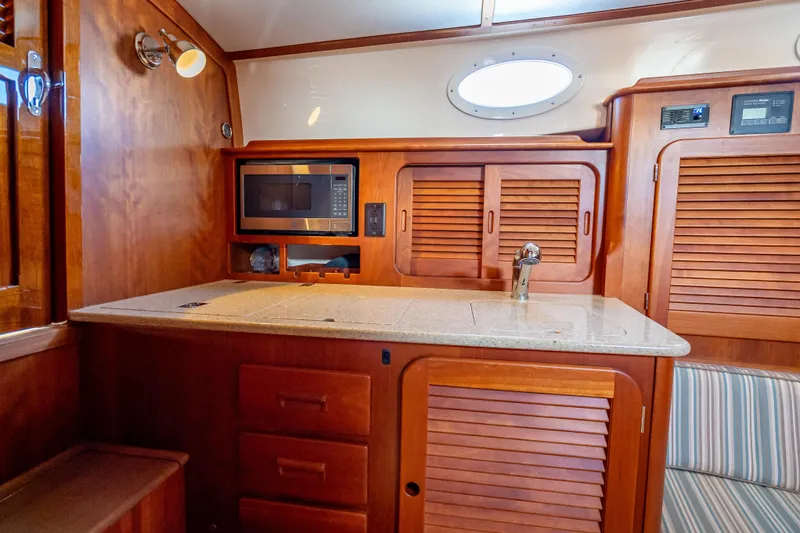 Gracious Yacht Photos Pics 2018 Hinckley Picnic Boat 37 MKIII interior with wooden cabinetry and kitchenette.
