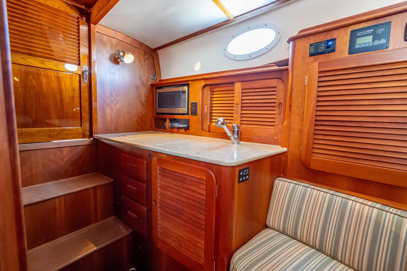 Gracious Yacht Photos Pics Hinckley Picnic Boat 37 MKIII 2018 interior with wooden cabinetry and compact kitchen area.