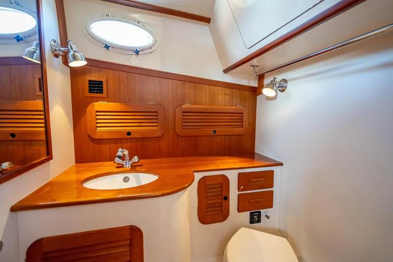 Gracious Yacht Photos Pics 2018 Hinckley Picnic Boat 37 MKIII bathroom with wooden cabinetry and modern fixtures.