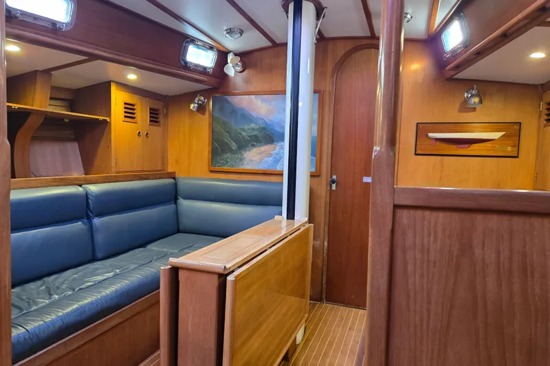 Simplicity Yacht Photos Pics Interior of 1986 Cambria 46 yacht with wooden paneling and blue seating.