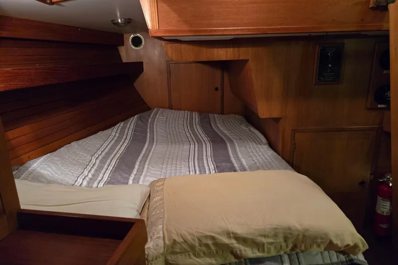 Simplicity Yacht Photos Pics Cozy cabin interior of 1986 Cambria 46 sailboat with wooden paneling and striped bedding.