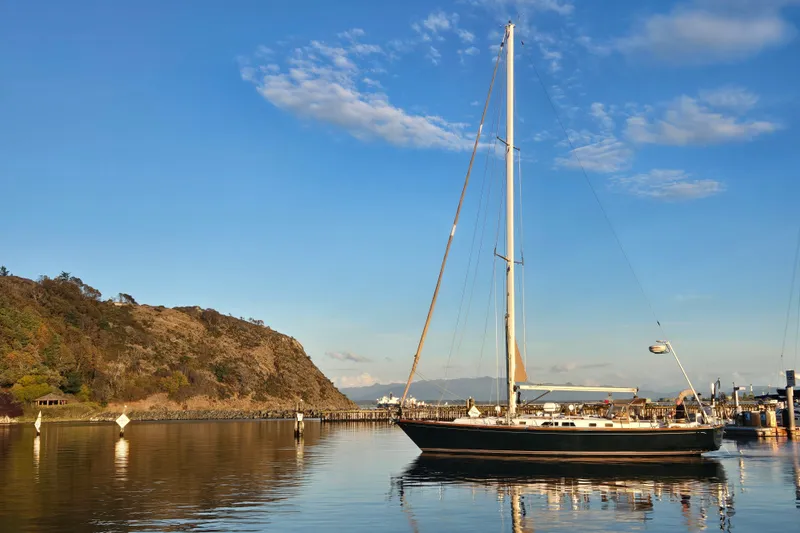 Simplicity Yacht Photos Pics Sailboat Cambria 46 (1986) docked in serene harbor with clear blue sky.