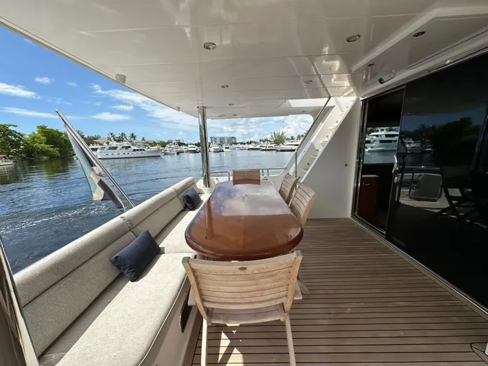 Unicorn Yacht Photos Pics Luxury yacht deck with wooden table, chairs, and scenic marina view. Hampton 658l Endurance 2020.