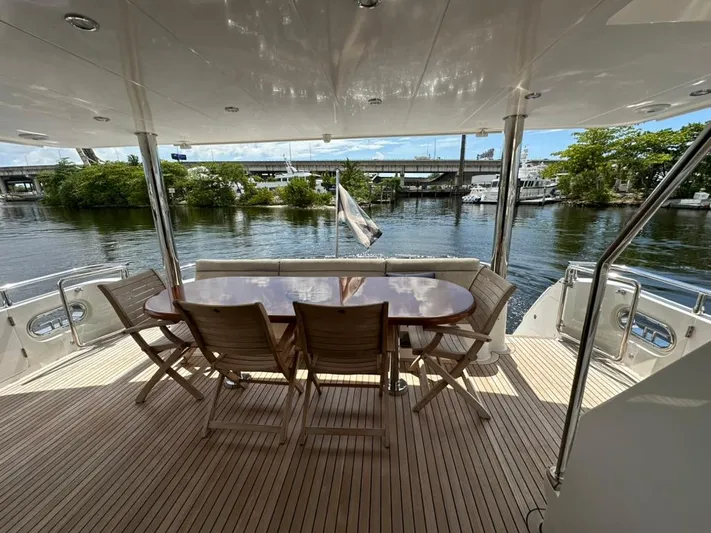 Unicorn Yacht Photos Pics Luxury yacht deck with wooden chairs and table, Hampton 658l Endurance 2020, scenic waterfront view.